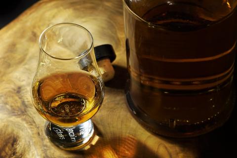 A Glencairn glass with brown liquor inside it