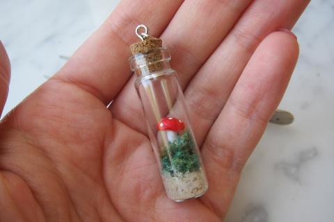 hand hold Terrarium Necklace with a mushroom and moss in a little bottle with a cork