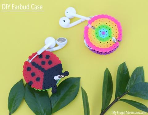 Two handmade Perler Bead circles containing a set of earbuds each. One is made to look like a ladybug while the other is a rainbow circle. 