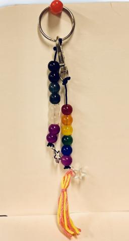 Sample image of two keychains for the craft. One keychain is made of black, grey, white, and purple beads, the asexual flag's colors. The second keychain is made of red, orange, yellow, green, blue, and purple beads, the rainbow pride flag's colors.