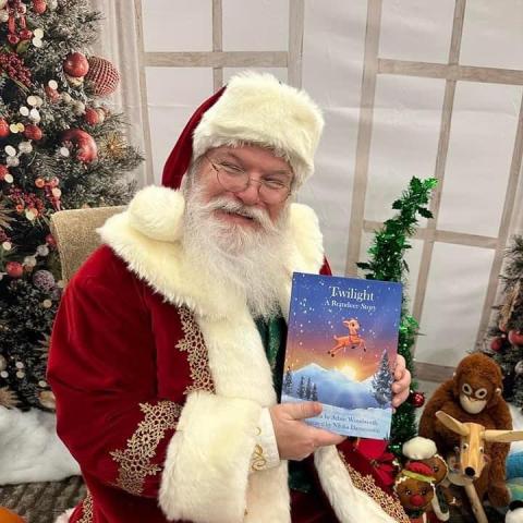 Photo of Santa holding the book "Twilight: the other Reindeer"