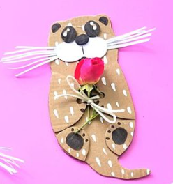 Cardboard otter holding a flower with a bow