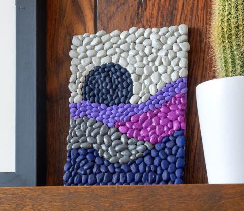 Photograph of canvas with mosaic composed of multicolored beans arranged in an abstract wave-like pattern 