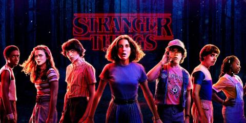 Image of the main cast of stranger things with the logo of the show in the background