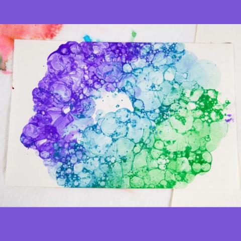 A photo on a purple background. Photo shows a bright painting with purple, blue and green, maybe from bubbles with splashes or darker and lighter colors. 