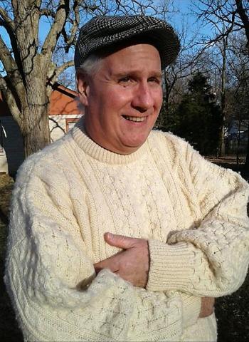 A man in a white sweater with a newsboy cap