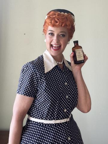 A woman dressed like Lucille Ball with curly red hair and a blue polka dot dress