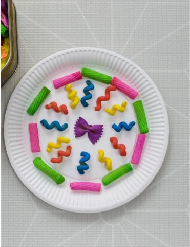 Colorful pasta glued into a paper plate in a mosaic pattern.