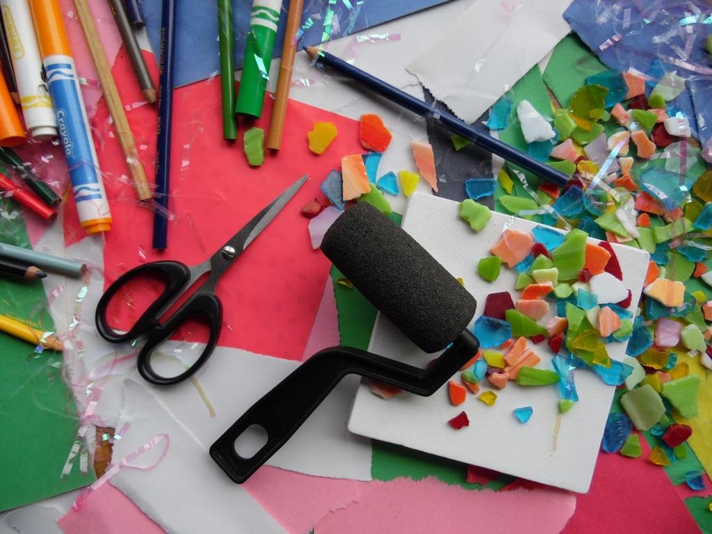 messy table with scissors, paint roller, paint splotches, pens and drawing tools