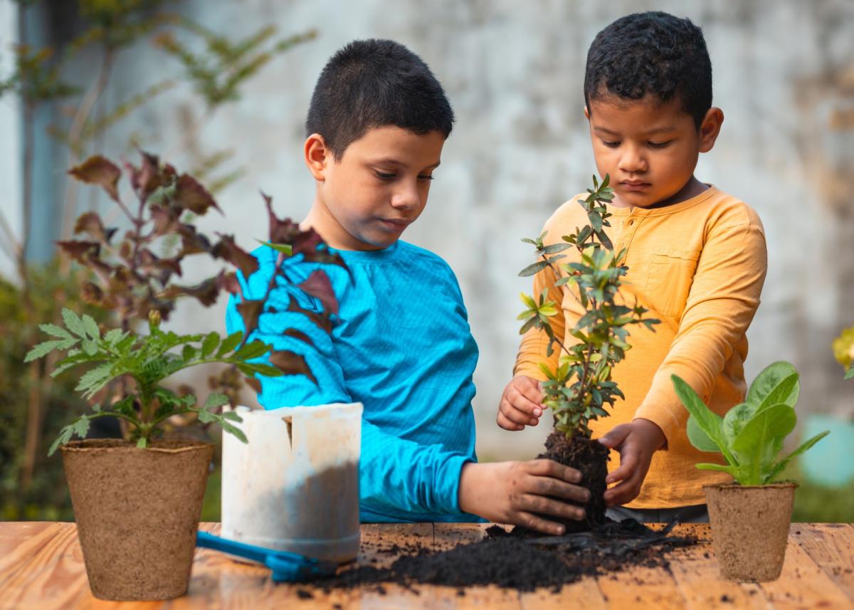 Two children planting with compostable pots