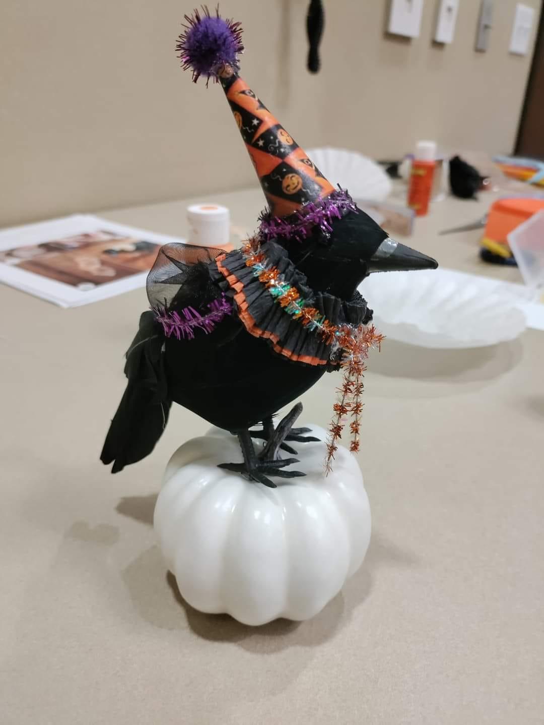 fake raven with whimsical pointed, orange and black hat