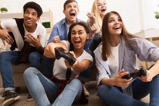 A group of teens playing a video game with big smiles.