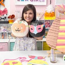 Young woman holding up two pumpkins with DIY masks on them