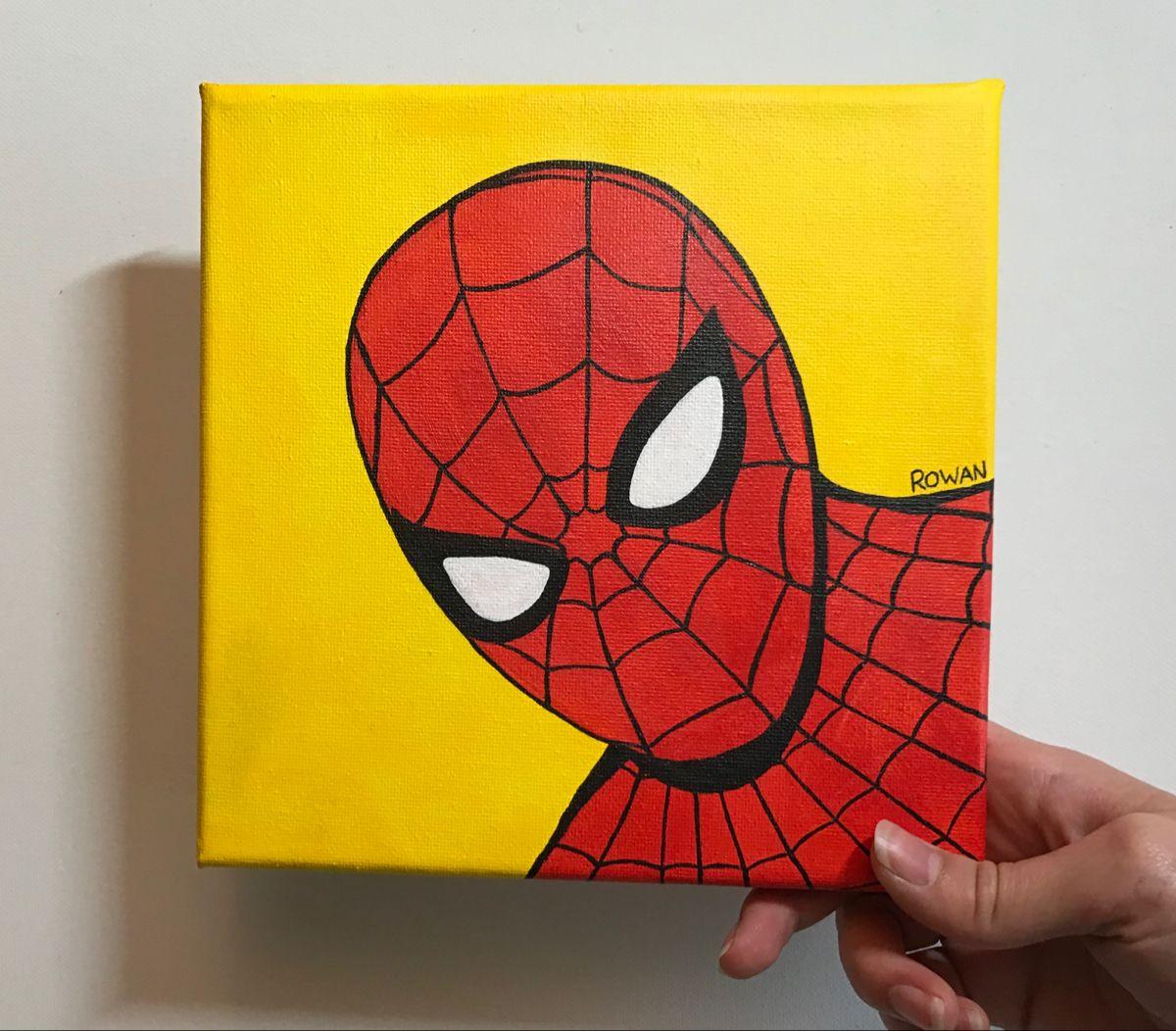 Hand holding a spiderman painting with yellow background